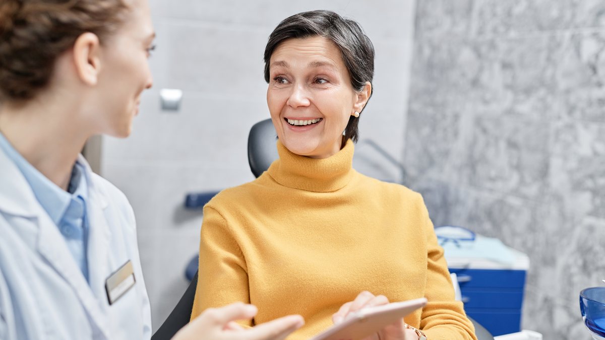 A smiling patient chatting with her dentist in the dental chair