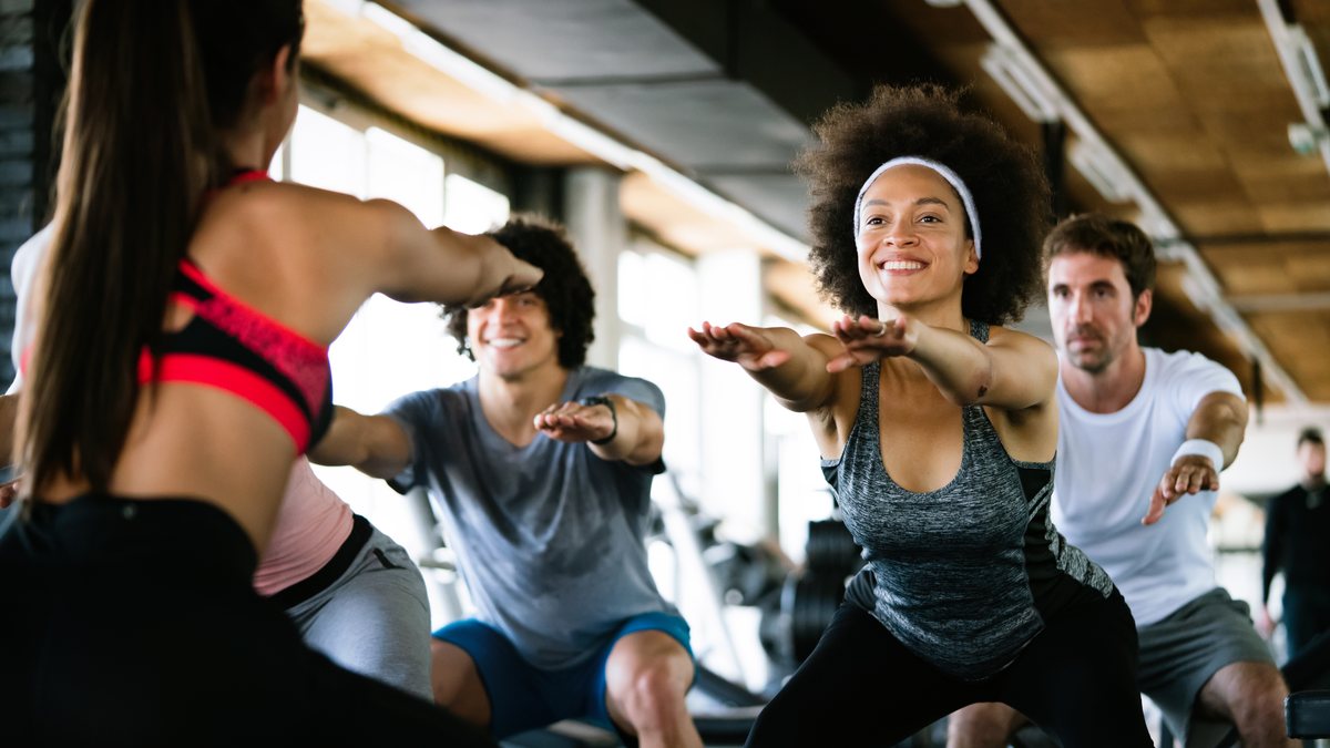 A group fitness class doing squats together in a gym