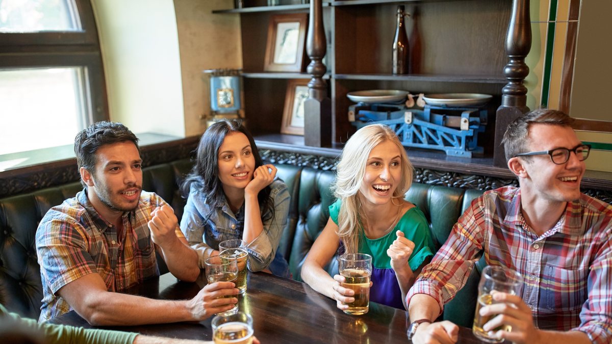 Friends laughing over pints of beer in a traditional pub booth